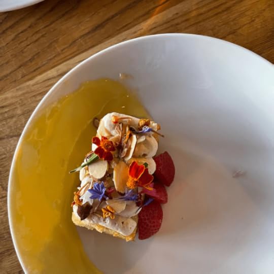 Slice of cake covered with dried flowers sitting in lemon curd.