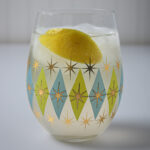 glass of ginger ale with a lemon wedge floating in it.