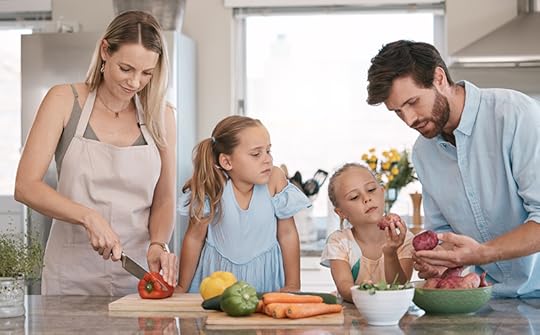 Photo of parents preparing a meal with their two daughters as they teach them about vegetables.