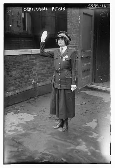 Black and white photograph of Captain Edna Pitkin standing in front of the police precinct holding her hand in the air as if making a pledge or promise.