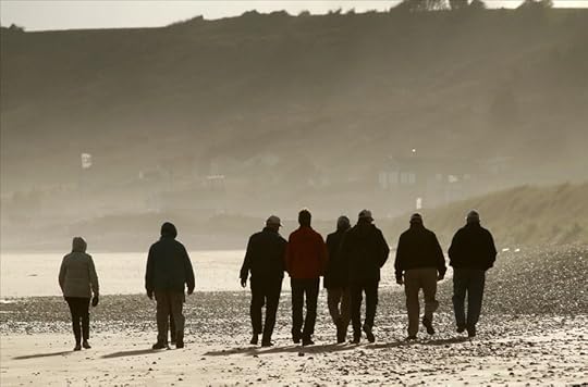 Photograph from behind of veterans walking the beaches of Normandy.