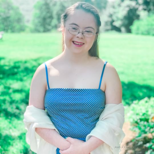 Penny stands outside wearing a blue dress for prom and smiles at the camera