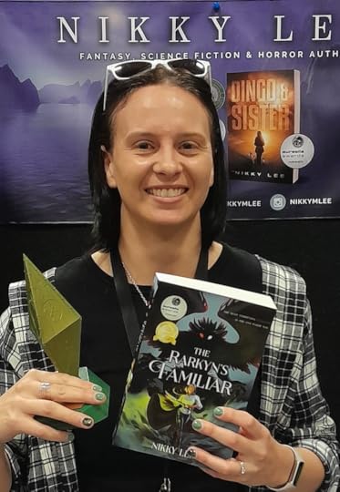 Nikky Lee holding a Sir Julius Vogel Award trophy and her book, The Rarkyn's Familiar.
