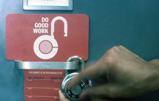 Photograph of a person's hand adjusting a padlock. It's attached to a handle with a sign nearby that says 