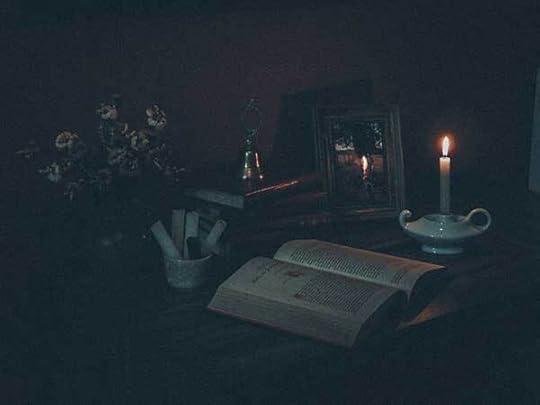 A book and a lit candle in the dark. The mood of the stories are gloomy.