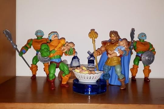 Randor holds baby Adam and Duncan holds baby Teela, while Adora is still in her cradle.