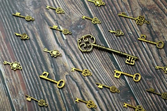 Image: ornately decorated, gold-colored antique keys are arranged on a wooden table.