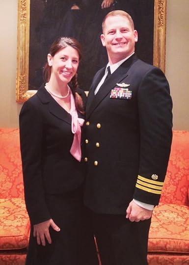 A Navy Commander in his dress blue uniform standing with his wife
