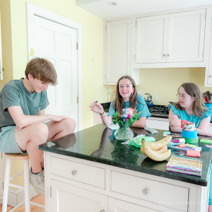 3 teens around the island in a yellow kitchen