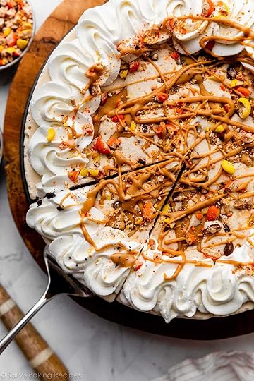 decorated peanut butter ice cream pie with Reese's Pieces, whipped cream, and peanut butter swirls on top.