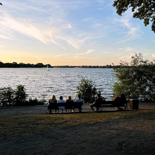 Menschen auf einer Bank vor dem Sonnenuntergang an der Außenalster