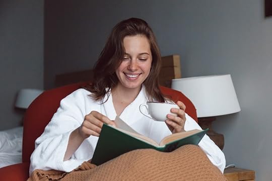 A smiling woman reading book. One of the reason YA fiction messaging speaks to all ages is because YA literature is so well-written.