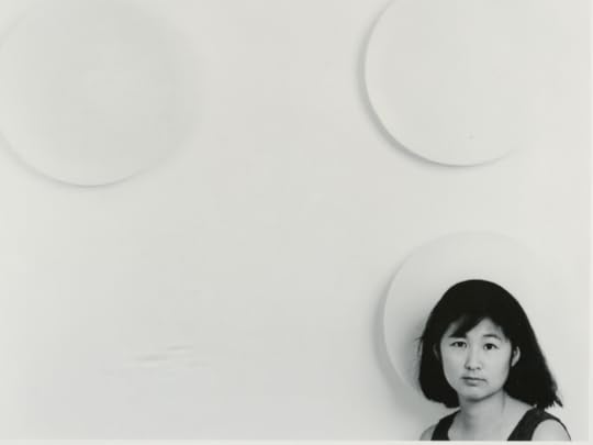 Black and white photo of a white wall with large circles in rows. Lin is visible at bottom right, with just her head and shoulders in the frame. She is not smiling.