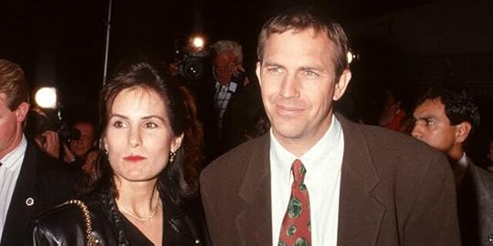 Kevin Costner in a brown suit looks off in the distance with his wife Cindy in black in California