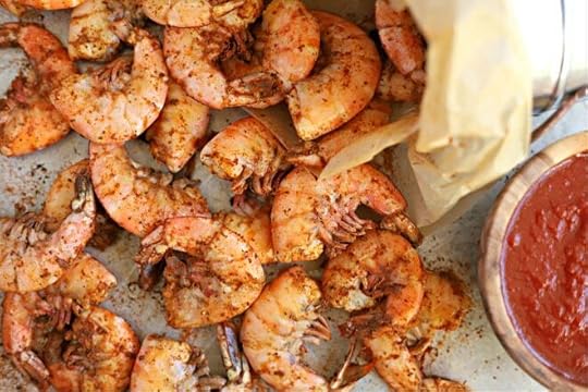 close up overhead shot of cooked old bay shrimp boil topped with extra old bay seasoning with wood bowl filled with cocktail sauce