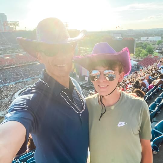 William and Peter wear cowboy hats and smile for the camera. A full stadium is in the background.