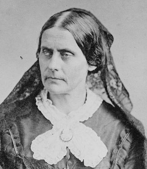 Photo shows Anthony late in life, seated, wearing a dark dress with a white lace collar held in place by a brooch. Her hair is parted in the middle and has a dark scarf at the back.