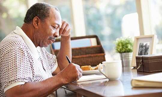 Older man sitting at a desk writing, how to write a memoir outline