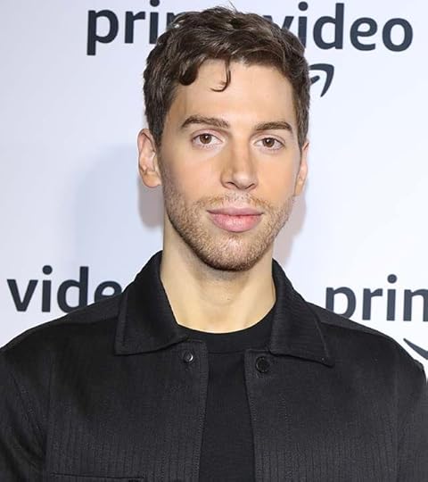 Jordan Gavaris in a black shirt and jacket on the carpet in Canada