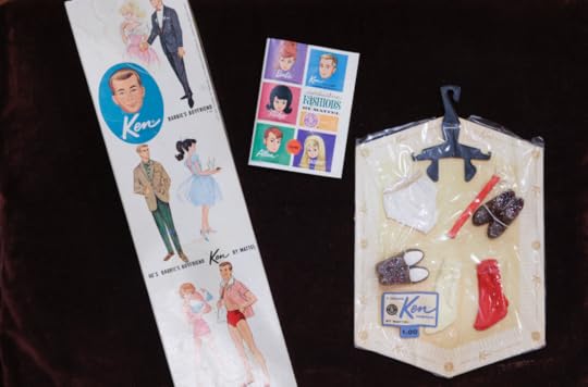 Accessories for the Ken doll, laid out against a black backdrop, some still in the original packaging. 