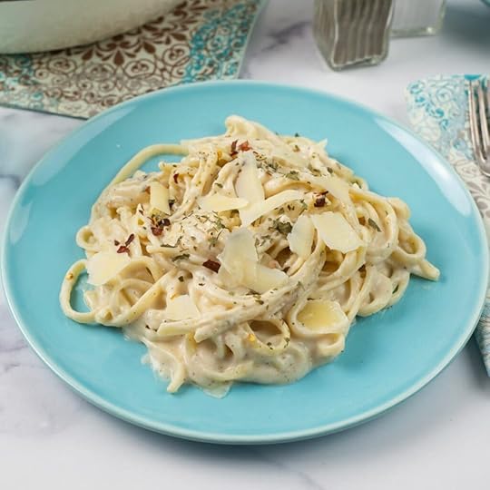 A serving of Spicy Alfredo Sauce garnished with Parmesan cheese and parsley on a dinner plate.