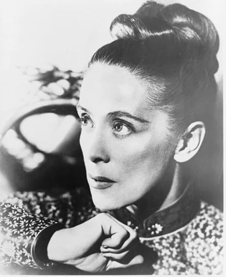 Black and white portrait of Martha Graham, head-and-shoulders, facing left. Her hair is in a bun, her right hand under her chin and eyes looking upward to her right