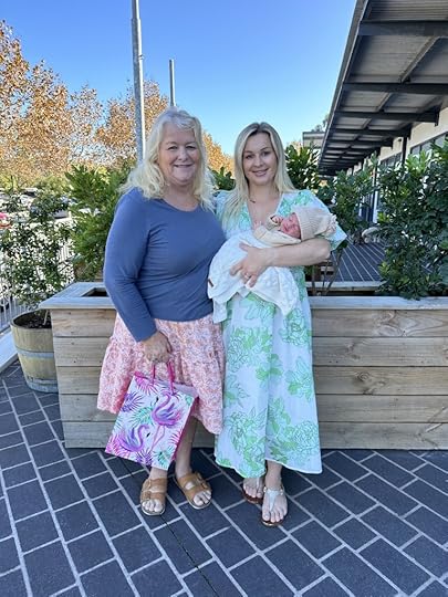 Older woman blonde hair standing next to younger woman blonde hair who is holding baby.