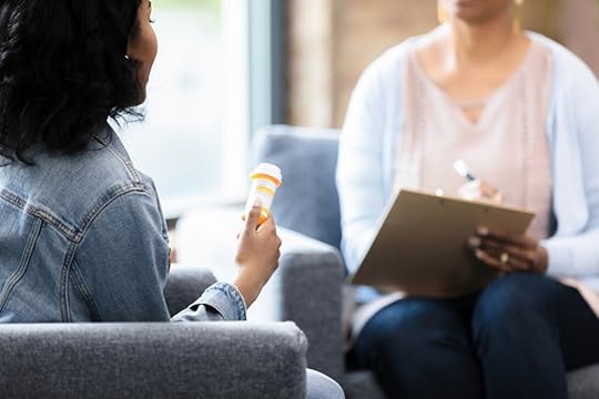The young woman holds onto the prescription bottle while she listens to medical professional