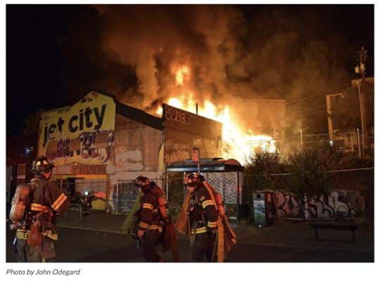 The condemned theater on fire, at night, while firefighters work on it. 