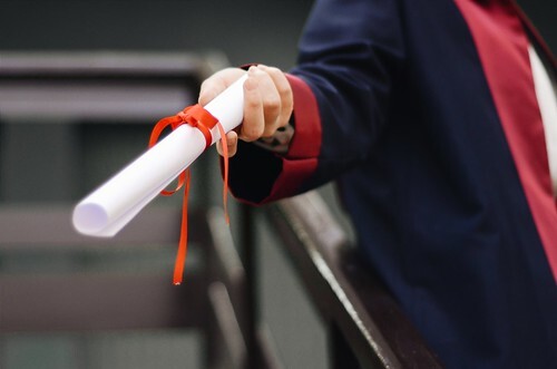 Person in a graduation robe with a diploma in hand. From Tips for Pursuing a Postgraduate Degree Abroad