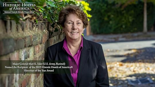 A woman in a suit leaning against a brick wall.