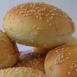 homemade hamburger buns stacked in a basket.