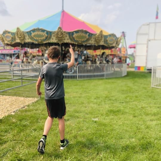 photo of a young teen pointing to a colorful carousel