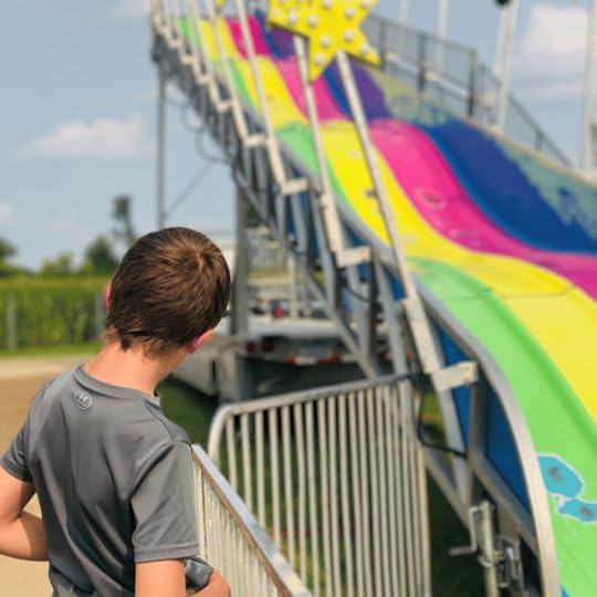 photo of a young teen looking a colorful slide at the county fair