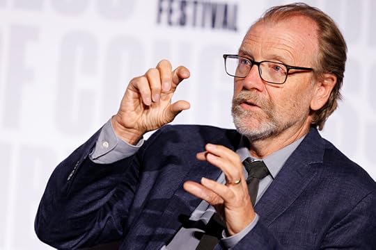 George Saunders, wearing a sport coat and a loosened tie, gestures with his hands while speaking
