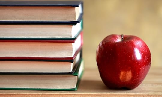 stack of five books and red apple on desk, book title capitalization