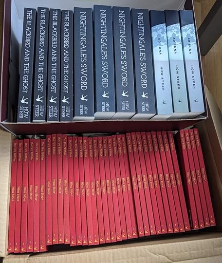 Two boxes full of books. The uppermost contains 4 copies of 'The Blackbird and the Ghost', 4 of 'Nightingale's Sword', and 3 of 'Ad Luna'. The lower box contains too many copies of 'The Fire Within'.