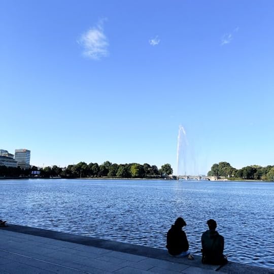 Zwei Menschen sitzen am Ufer der Binnenalster. Jungsernsgtiegseite, im Hintergrund die Alsterfontäne