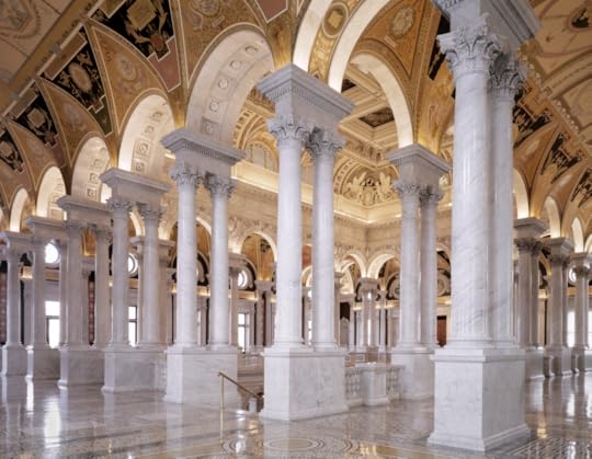 Great Hall at the Library of Congress's Thomas Jefferson Building. Dozens of white marble columns support an arched ceiling painted deep gold.