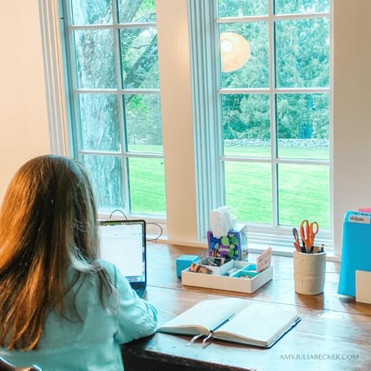 Amy Julia sits at a desk with facing large windows