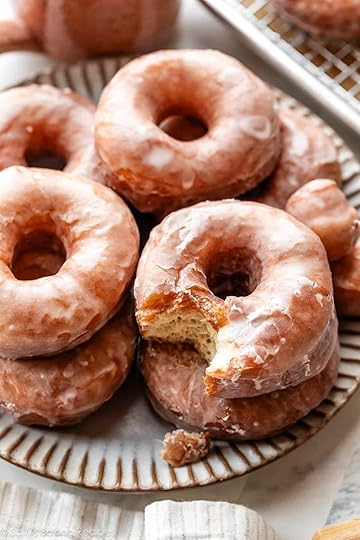 doughnuts piled on gray plate with one with bite taken out.
