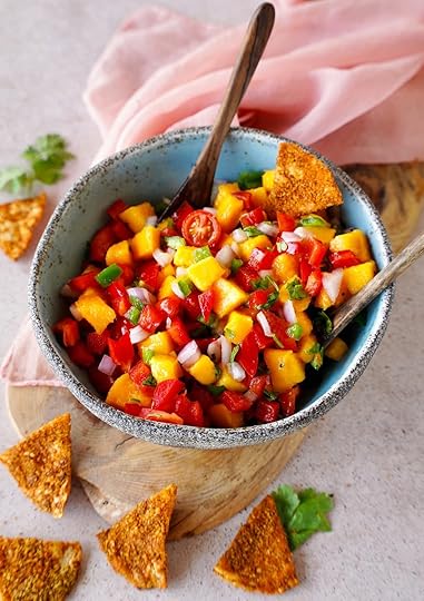 mango salsa in bowl with wooden spoons and tortilla chips