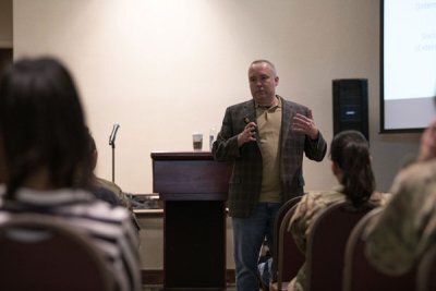 Psychologist Craig Bryan speaks to a room of David Grant USAF Medical Center mental health care providers at Travis Air Force Base, California, in 2022. Bryan, a leading national expert on military suicide, taught advanced skills training for the providers during a two-day session. Photo by Lan Kim, courtesy of the U.S. Air Force. 