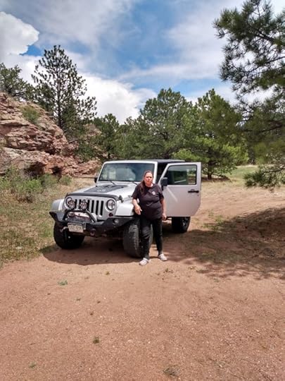 Author Kaye Lynne Booth in the mountains, standing in front of a Jeep.