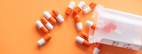 A photo of orange and white medication pills spilling across an orange background to illustrate the blog post 