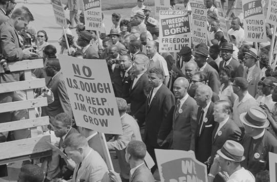Photograph showing civil rights leaders, including Martin Luther King, Jr., surrounded by crowds carrying signs.