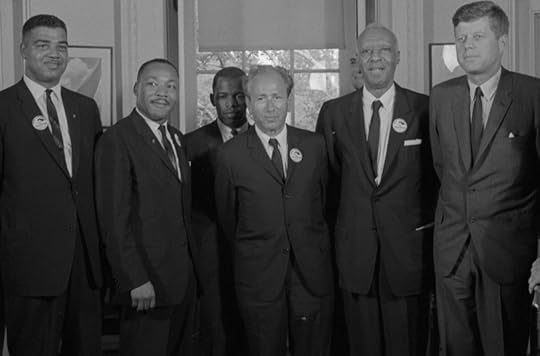 Black and white photo from Oval Office, with men in suits and ties looking at photographer