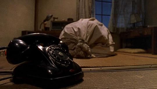 A man bound in a bag next to a black rotary phone in Miike's
