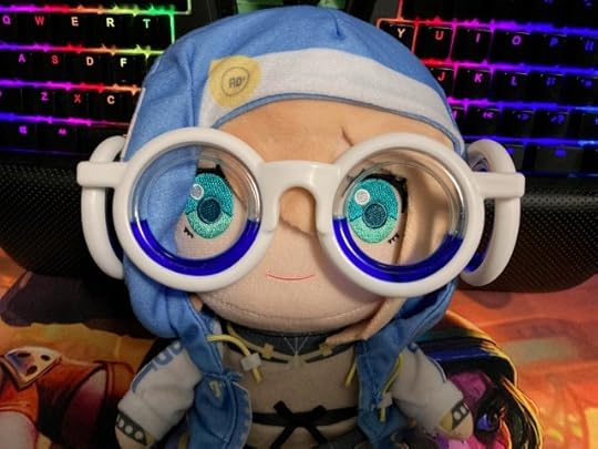 A picture showing an adorable plushie of Bridget from the video game Guilty Gear. This plushie is wearing a pair of goofy-looking motion sickness glasses. Its bright cyan-eyes stare into the camera.