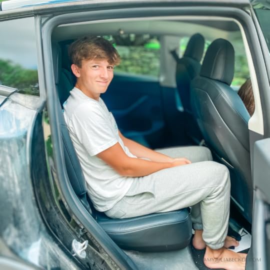 William sits scrunched in the back seat of a car with his knees almost touching the seat in front